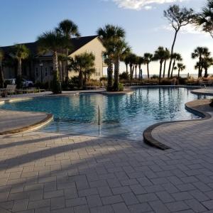 a swimming pool with palm trees and a house at HONU KAI - 3 Bedroom Townhouse townhouse in Jekyll Island