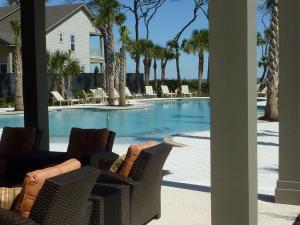 Blick auf einen Pool mit Stühlen und Bäumen in der Unterkunft HONU KAI - 3 Bedroom Townhouse townhouse in Jekyll Island