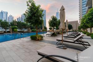 a row of lounge chairs with umbrellas and a pool at Dream Inn Apartments- Boulevard Heights in Dubai