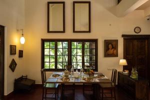 a dining room with a table with chairs and a window at amã Stays & Trails Asanji Wadi, Alibag in Alibaug