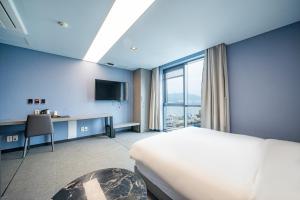 昌原市にあるLouis Boutique Hotelのベッドと大きな窓があるホテルの部屋