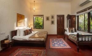 a bedroom with a bed and a couch and a window at amã Stays & Trails Asanji Wadi, Alibag in Alibaug