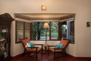 Habitación con 2 sillas, mesa y ventana en amã Stays & Trails Asanji Wadi, Alibag en Alibaug