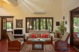 un soggiorno con divano, sedie e tavolo di amã Stays & Trails Asanji Wadi, Alibag ad Alibaug