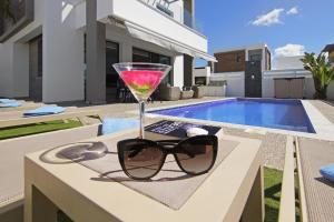 a drink and sunglasses on a table next to a swimming pool at Villa Martha in Protaras