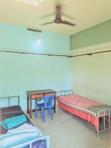 a room with two beds and a table in it at VKR MENS ROOM (Gents Only) in Kozhikode