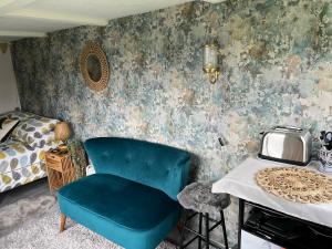 Bothy hut في ترينج: غرفة نوم بها كرسي ازرق وسرير