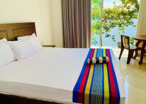 um quarto com uma cama com um cobertor colorido em New Heaven em Ambalangoda