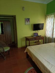 a bedroom with a bed and a desk and a television at Kadalamma Beach Homestay in Alleppey