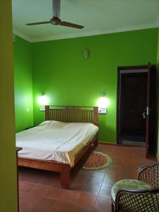 a green bedroom with a bed and a ceiling fan at Kadalamma Beach Homestay in Alleppey
