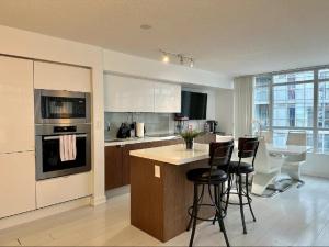 a kitchen with a island with bar stools at 1200+sqft Luxury Corner Suite in Toronto