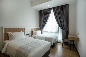 a hotel room with two beds and a desk and a window at Opus KL Residences by Premium Hospitality in Kuala Lumpur