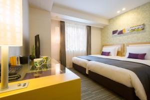a hotel room with two beds and a desk at Hotel Resol Trinity Kanazawa in Kanazawa