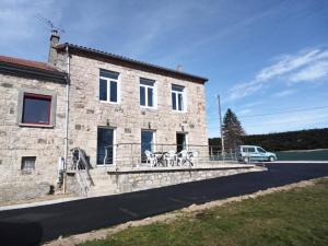 uma casa de pedra com uma varanda em frente em La bonne adresse em Sainte-Sigolène