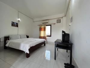 a bedroom with a bed and a desk and a television at Vang Vieng Backpackers Hostel in Vang Vieng