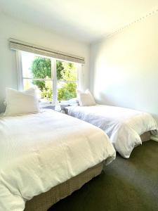 two white beds in a room with a window at Walnut House Mildura in Mildura