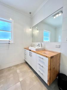 a white bathroom with a sink and a mirror at Walnut House Mildura in Mildura