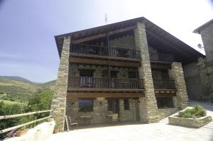 a large stone building with a balcony and tables at L'Era de Cal Bastida in Estamariu