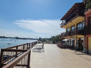 a boardwalk with chairs and a building next to the water at Apartmánový Garni Hotel Relax in Senec