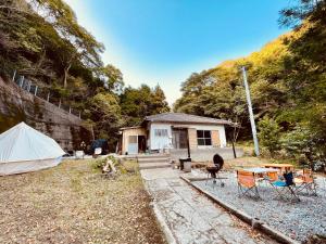 une maison avec une tente, une table et des chaises dans l'établissement ワイルドライフ　森風, à Hiki