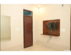 Habitación con TV y pared con espejo. en Hotel Moody Moon, Bareilly, en Bareilly