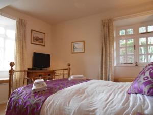 1 dormitorio con 1 cama, TV y ventana en The Granary, Old Corn Mill, Yorkshire Dales, en West Burton
