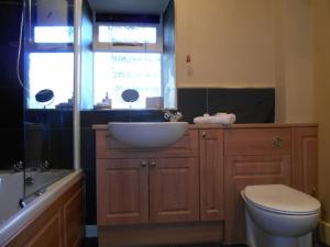 een badkamer met een wastafel, een toilet en een bad bij The Granary, Old Corn Mill, Yorkshire Dales in West Burton