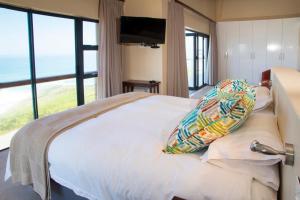 um quarto com uma cama e vista para o oceano em Dolphins on Six Self Catering Apartments em Wilderness