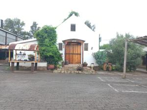 a white church with a wooden door on a street at The Grey's Inn in Machadodorp