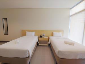 two twin beds in a room with a window at Kaizen Suites in Manila