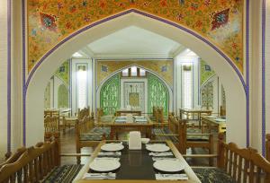 a dining room with tables and chairs and a colorful wall at Atlas in Bukhara