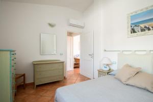 a bedroom with a bed and a dresser and a table at Sea Shell - Klodge in Olbia