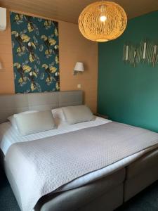 1 dormitorio con 1 cama grande y pared verde en Hotel SPA Restaurant Au Cheval Blanc, en Ribeauvillé