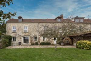 a large stone house with a tree in the yard at Maison Valeli - Maison de charme à 1h de Paris in Lavilletertre