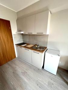 a small kitchen with a sink and white cabinets at OSPER Rooms in Łomża