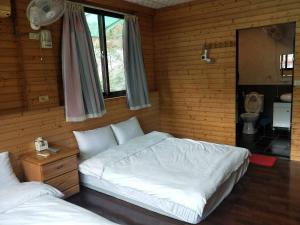 een slaapkamer met 2 bedden en een toilet. bij Meiting B&B in Shuili
