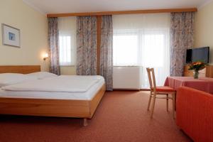 a bedroom with a bed and a chair and a television at Wohlfühl Hotel Wiesenhof in Grafendorf bei Hartberg +35 photos