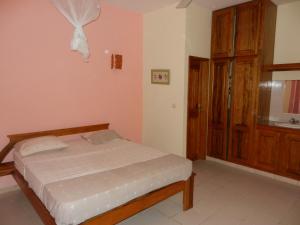 Schlafzimmer mit einem Bett und einer Holztür in der Unterkunft Villa au Tamtam in Gandigal
