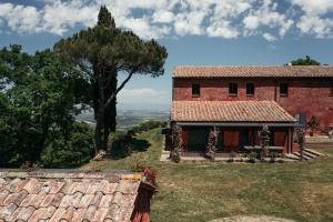 una casa en la cima de una colina con un árbol en Rural Tuscany - Luxury Villa San Bartolomeo, en Sarteano