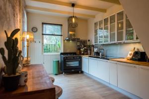 a kitchen with white cabinets and a black stove at De Klokkenluider in Hollum