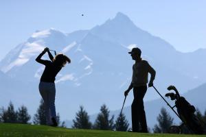 two people and a dog on a golf course at Chalet Diognysos B&B in Crans-Montana