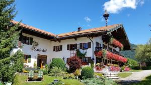 un grande edificio bianco con fiori nel cortile di Pension Staufenhof a Inzell