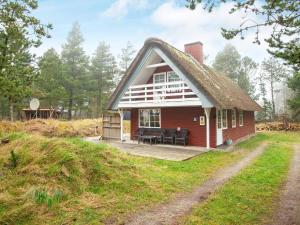 a small red house with a thatched roof at Modern Holiday Home in Rømø with Sauna in Toftum