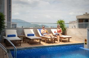 two people sitting on a deck next to a swimming pool at Maris Hotel Nha Trang in Nha Trang