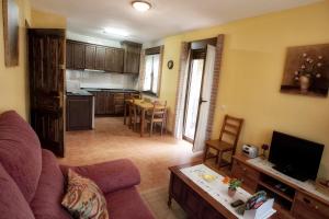 ein Wohnzimmer mit Couch und Tisch und eine Küche in der Unterkunft Apartamentos el Caserón in Soto de Cangas