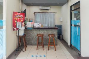 - une cuisine avec deux tabourets et un comptoir dans un restaurant dans l'établissement RedDoorz Plus near Universitas Indonesia, à Jakarta