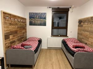 two beds in a room with wooden walls at Aparthotel Waldhorn Wohnung Allgäustyle in Stuttgart
