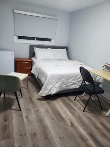 een slaapkamer met een bed, een bureau en een stoel bij Maxwell Esabu in Toronto