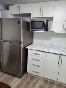 een keuken met een roestvrijstalen koelkast en witte kasten bij Maxwell Esabu in Toronto