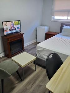 een slaapkamer met een bed en een tv op een open haard bij Maxwell Esabu in Toronto